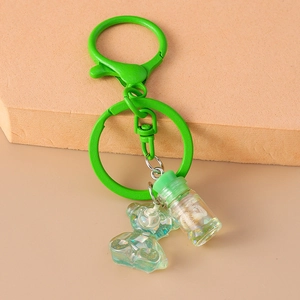 Detail of green iridescent resin bear charm with seashell glass bottle on a spring keychain