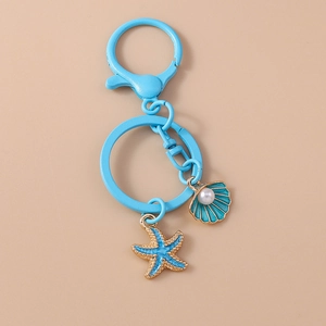 Detail of blue starfish and seashell keychain with white pearl on a gold-edged alloy