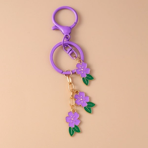 Close-up of purple cherry blossom keychain with gold accents and enamel flower pendants