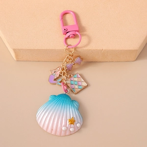 Detail of seashell keychain with mermaid charm and pearl accents on a pink lobster clasp