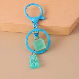 Close-up of blue metal keychain featuring a green ice cube and gradient resin bear