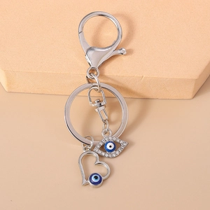 Detail of silver evil eye keychain with white rhinestones and a hollow heart pendant
