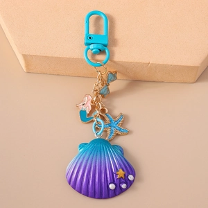 Detailed close-up of shell and mermaid keychain with blue metal spring clasp on stand