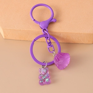 Detail of purple gummy bear keychain with metallic lobster clasp on orange background