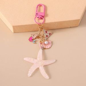 Detail of pink shell and mermaid charms on a star-shaped keychain with gold chains