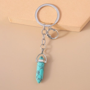 Detailed macro view of the moon charm and hexagonal turquoise pendant on a silver keychain