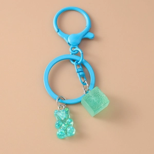 Detail of blue metal keyring with transparent gummy bear and matte green resin cube