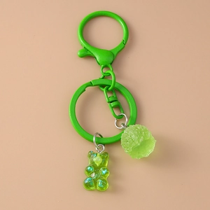 Detail of green resin gummy bear keychain with glitter and fuzzy pom pom ball