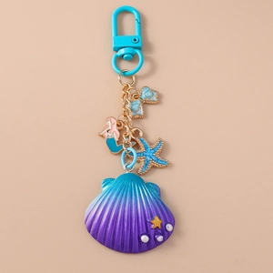 Detail of seashell and mermaid keychain with blue starfish on golden chain
