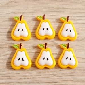 Set of six resin pear slices with seeds and green leaves on wood background