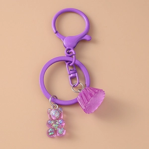 Detailed macro view of purple glitter gummy bear and cupcake charms on a metal keychain