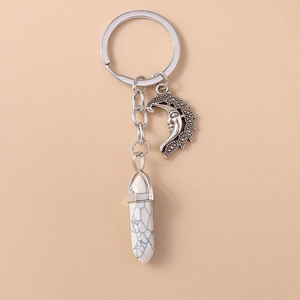 Detail of vintage moon pendant and white turquoise hexagonal prism on a silver keychain