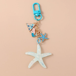 Detailed close-up of a blue starfish keychain with a pink mermaid and glitter charm