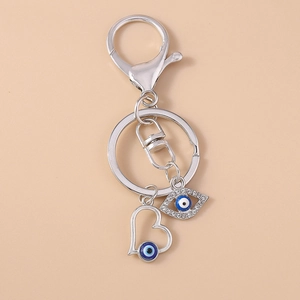 Detail of silver evil eye keychain featuring hollow heart and crystal eye charms