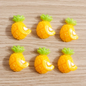 Close-up of six yellow resin pineapple charms on wood for DIY craft and phone case decor
