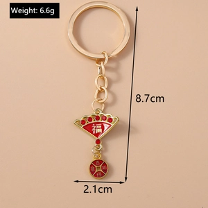 Detail of golden keychain with red fan pendant featuring Fu character and lucky coin