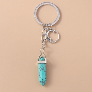 Detail of moon pendant and hexagonal turquoise stone on a silver keychain