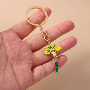 Detail of hand-held Chinese style keychain with yellow fan and green bamboo pendant
