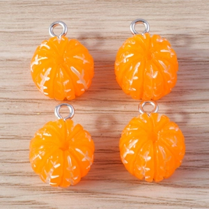 Detailed view of four orange resin citrus charms with metallic loops on wood