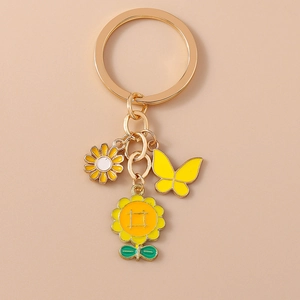 Détail de breloques tournesol, marguerite et papillon sur un porte-clés doré