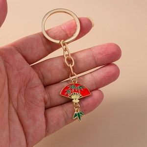Detail of red traditional Chinese fan keychain with green bamboo leaves and gold metal ring