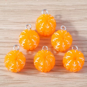 Close-up of six resin orange citrus charms with metal rings on a light wood background