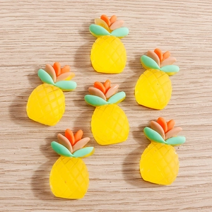 Flat lay of six yellow resin pineapple charms with grid texture on a wooden background