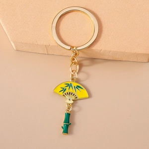 Detailed view of a gold keychain featuring a yellow enamel folding fan and green bamboo charm