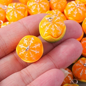 Macro shot of realistic resin orange charms for DIY jewelry with silver metal hooks