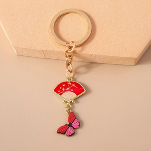 Detail of red folding fan and butterfly charm on a golden Chinese style keychain