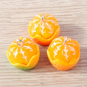 Macro detail of three resin orange slice pendants with realistic texture on wood background