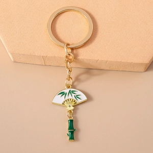 Detail view of a gold Chinese style fan keychain with green enamel bamboo patterns