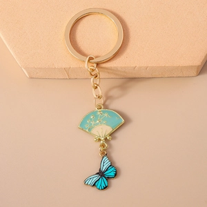 Macro view of Chinese style fan and butterfly charms on a golden metal keychain
