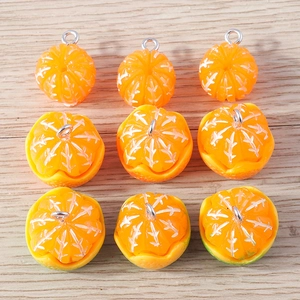 Macro detail of resin orange segment charms with silver metal rings on wood background
