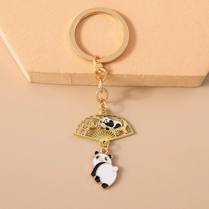 Detail of golden panda keychain with fan pendant and red flowers on stone base