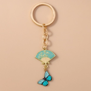 Detail of gold keychain with teal fan charm and blue butterfly enamel pendant