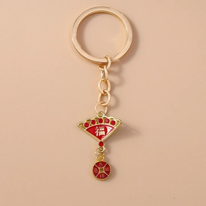 Detailed macro of golden Chinese fan keychain with red enamel and auspicious symbols