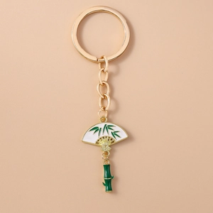 Detail of golden metal keychain with green bamboo joint and painted folding fan charm