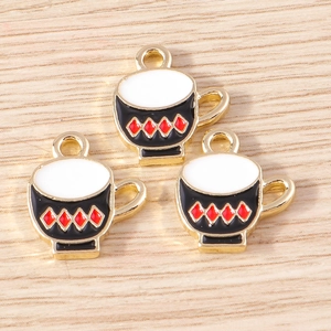 Macro shot of three cartoon tea cup enamel charms with red diamond pattern on wooden background