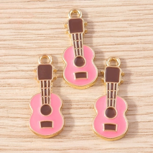 Detailed view of pink enamel guitar pendants with gold edges on wood surface