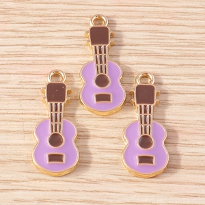 Detailed view of three purple and gold enamel guitar charms for DIY jewelry making