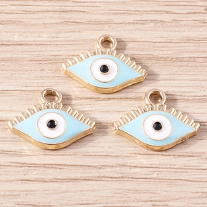 Trois pendentifs œil bleu en émail et métal doré sur un fond en bois clair