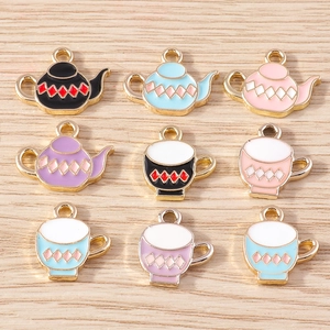 Macro shot of colorful enamel teapot and teacup alloy charms with gold borders for DIY crafts