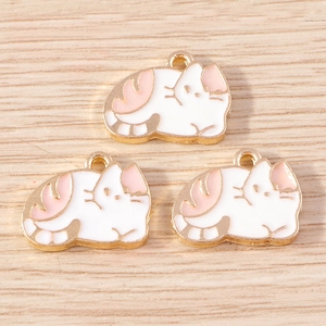 Close-up of three cute white and pink enamel cat pendants with gold metal edges