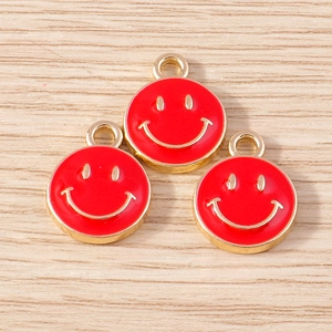 Close-up of three red enamel smiley face charms with gold trim on wooden background