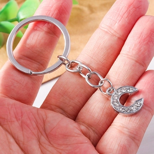 Detailed view of hand holding a silver letter C keychain with sparkling rhinestones