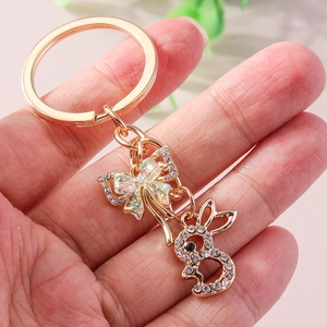 Handheld gold keychain with hollow bow and rabbit charms inlaid with sparkling rhinestones