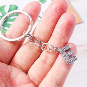 Macro shot of a silver letter E keychain pendant with sparkling crystal inlay