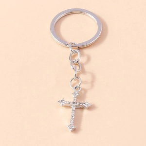 Vue détaillée d'un porte-clés croix en alliage argenté avec strass blancs sur fond rose