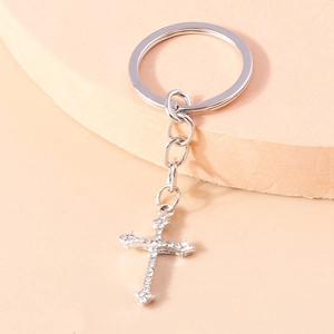 Porte-clés croix gothique argentée avec strass brillants sur fond minimaliste
